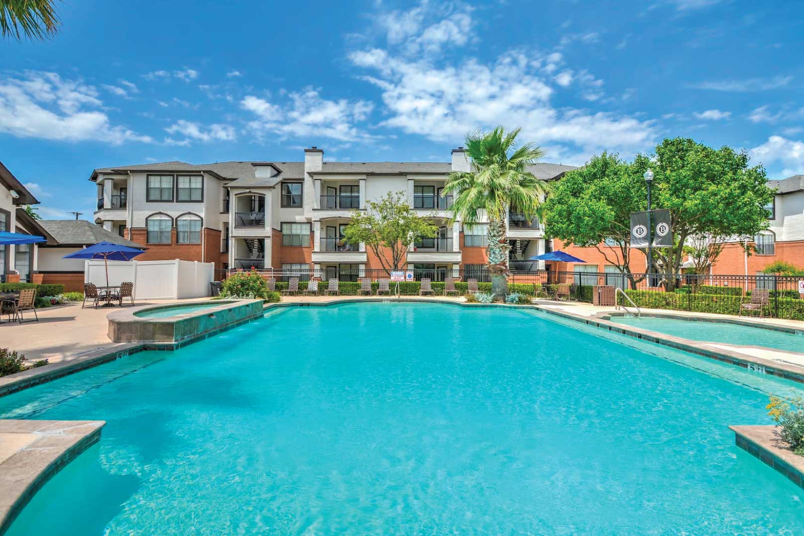 one of two resort-style pools surrounded by green trees