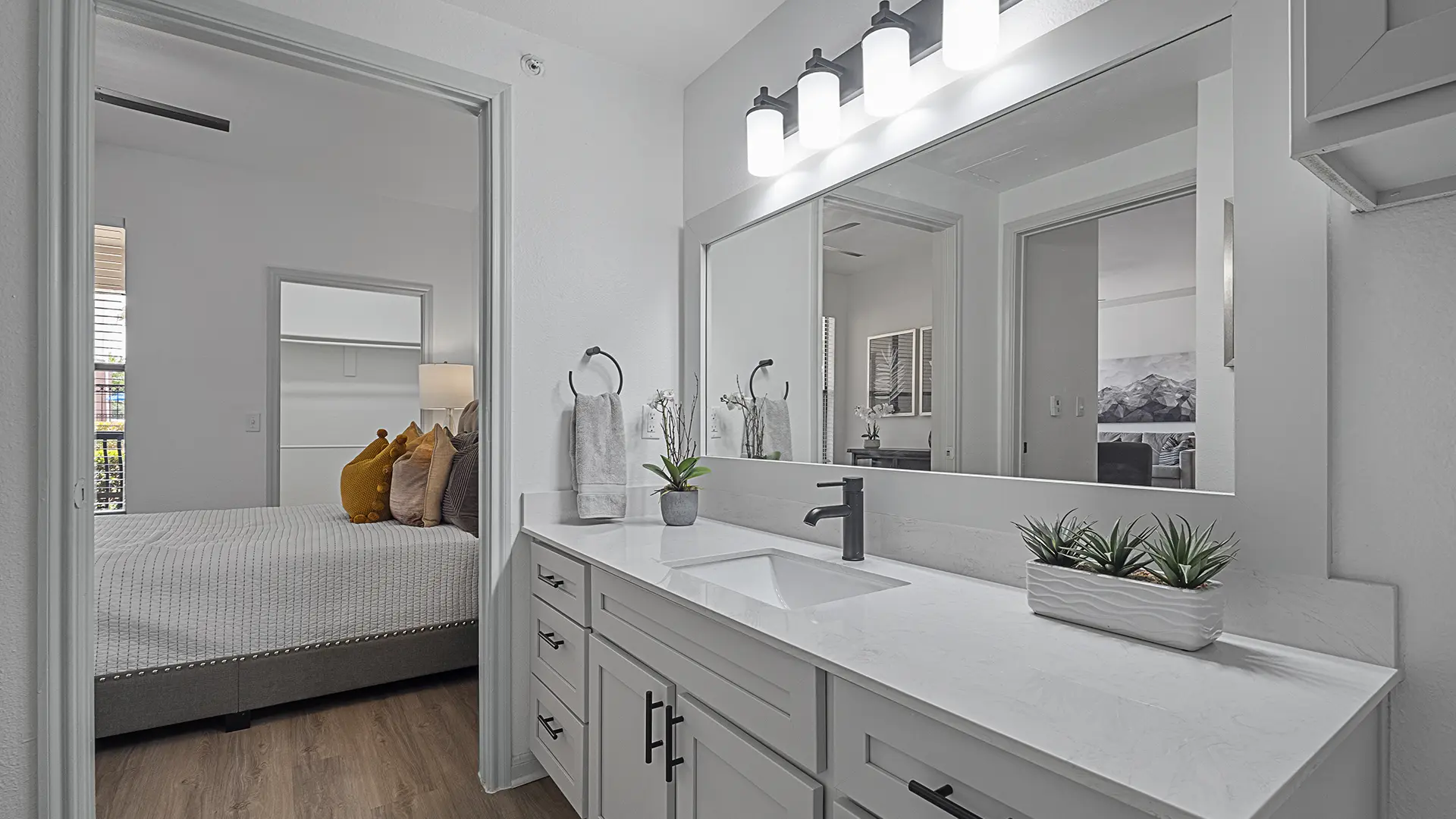 model bathroom leading to bedroom with plank flooring